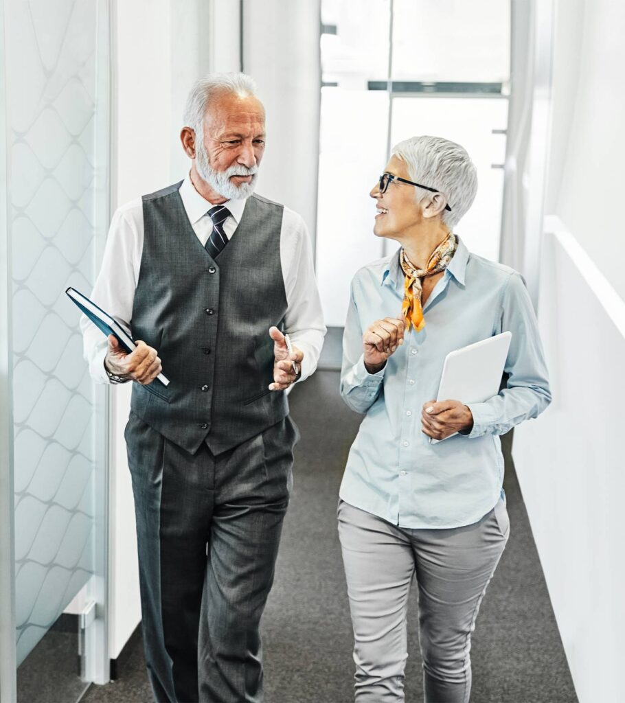 Two business professionals walking together down a modern office hallway | Featured image of the Retirement Lawyers page